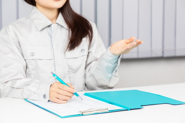 作業服姿でバインダーに記入する女性