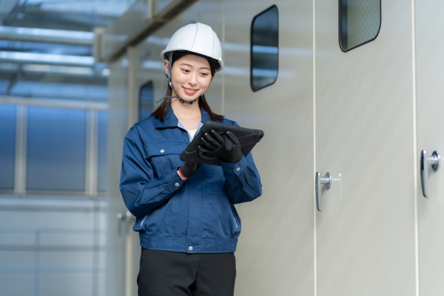 タブレットを操作するヘルメット姿の女性。