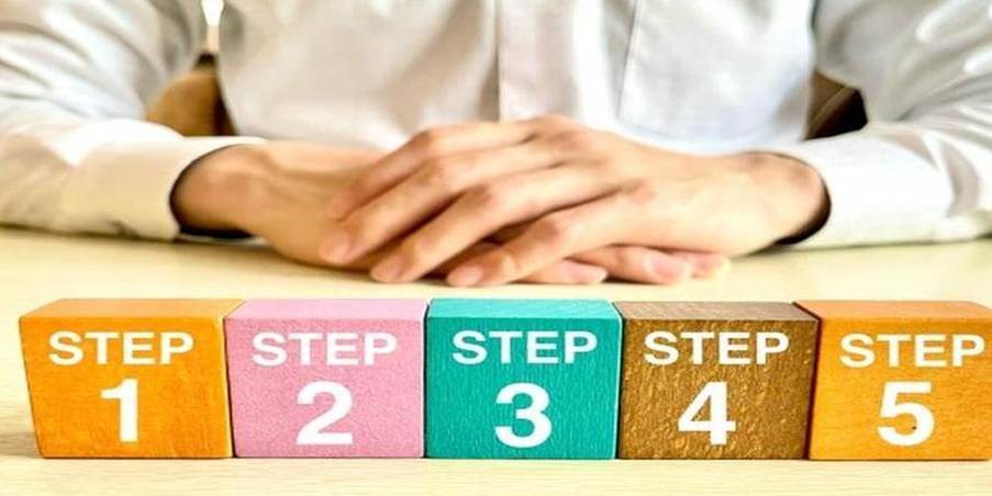 STEP1からSTEP5までのカラフルなブロックと説明する人物の手元