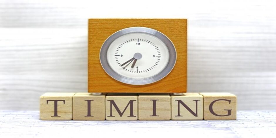 「TIMING」の文字とアナログ時計が載った木製キューブのイメージ