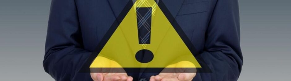 スーツ姿の男性が警告マークを掲げる様子