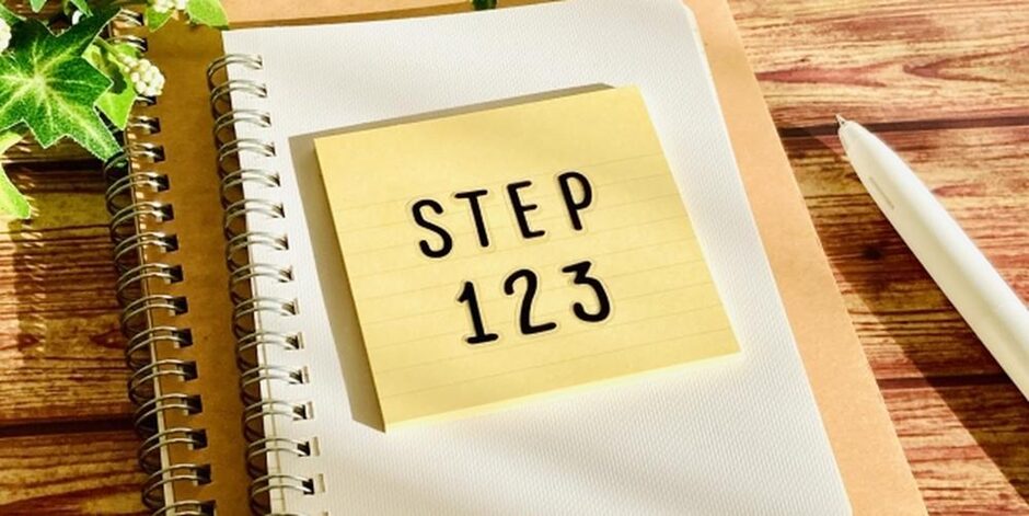 STEP123と書かれた付箋が貼られたノートとペン