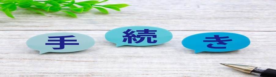 吹き出し型のパネルに書かれた『手続き』の文字とペン、観葉植物が置かれたデスク上のイメージ