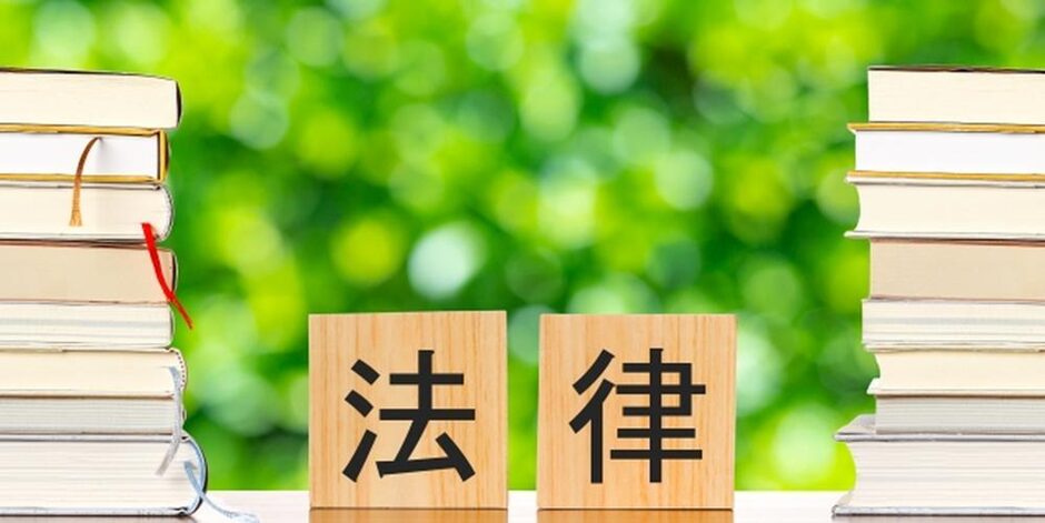 法律と書かれた木札と積み上げられた法律書籍